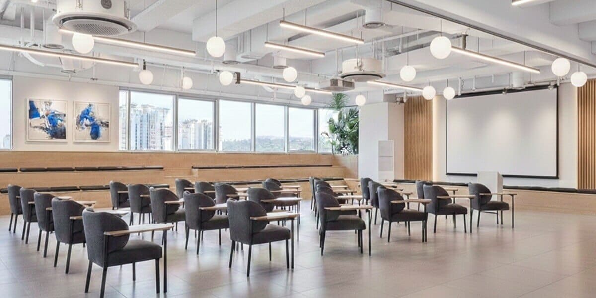 Modern corporate seminar room with tiered wooden seating and curated blue abstract paintings, demonstrating how art management software organizes collections in large-scale professional training environments.
