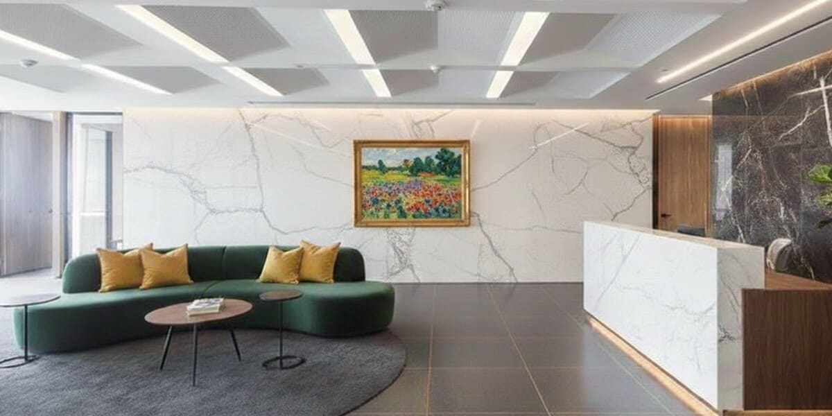 Office reception featuring a white marble wall and a gold-framed impressionist landscape, demonstrating high-end art asset management for corporate foyers.